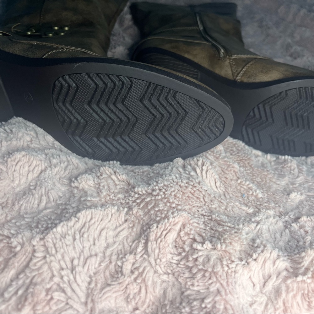 Brown heeled boot with zipper on the inside of each leg. Has strap with buckle